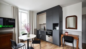 A modern kitchen with a dining area, a TV displaying WiFi details, and a large mirror. - Base Lausanne (Lausanne)