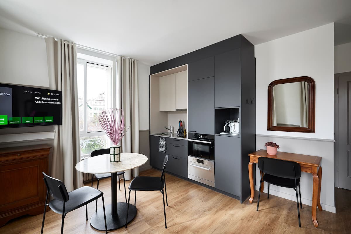 A modern kitchen with a dining area, a TV displaying WiFi details, and a large mirror.