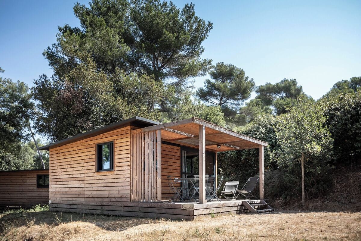 Eine Holzhütte mit überdachter Veranda und Sitzgelegenheit im Freien.
