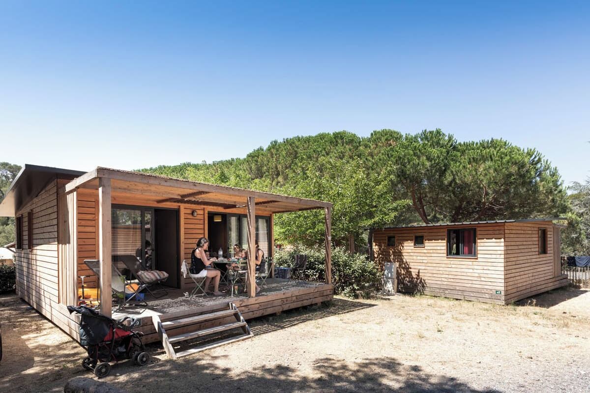 Eine Holzhütte mit einer Veranda und einer kleinen separaten Hütte.