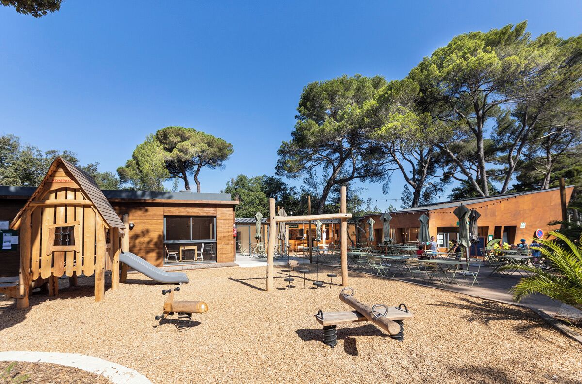 A playground with a slide, swings, and a wooden playhouse.