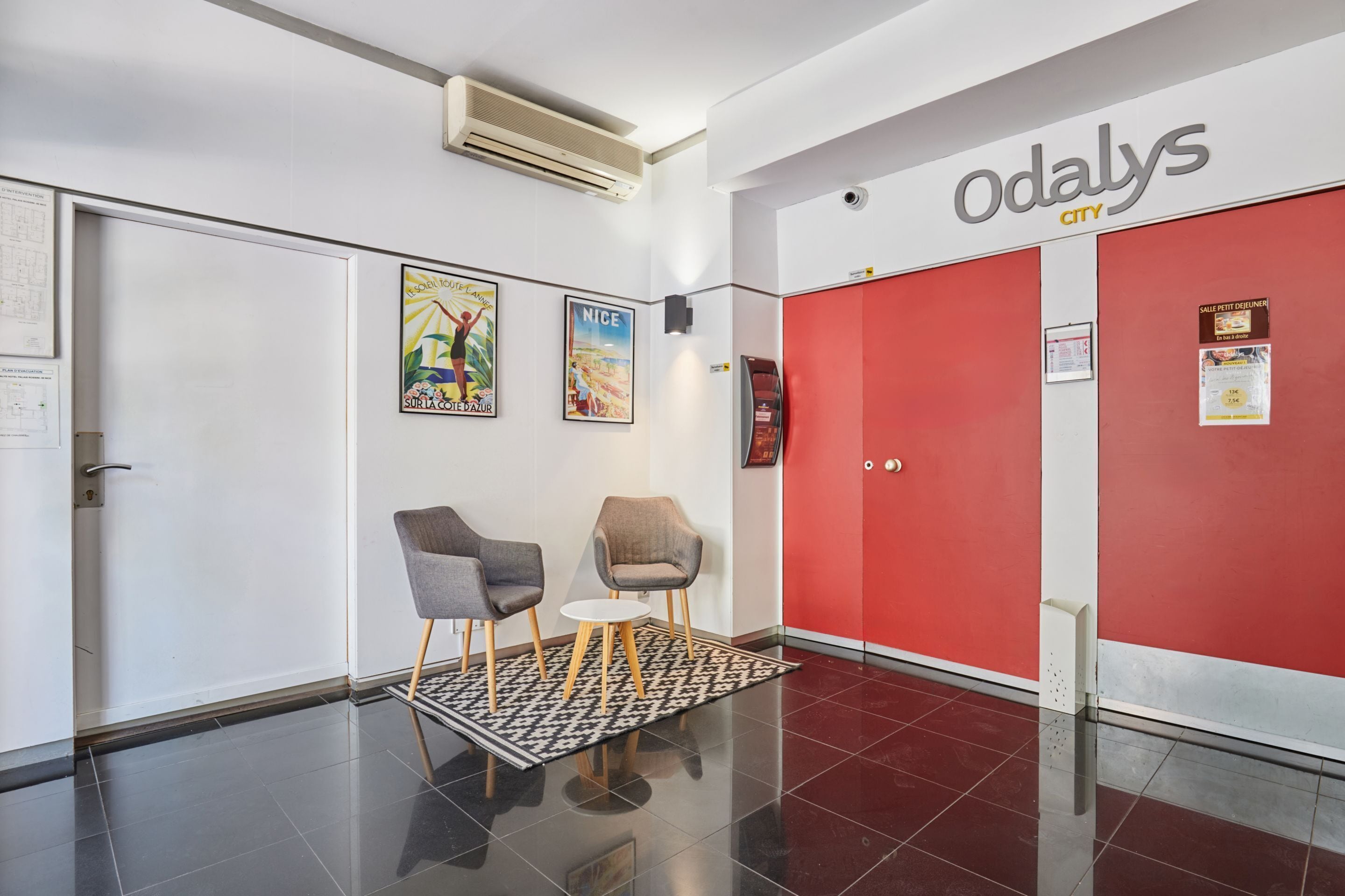 A modern interior with a red wall, two chairs, a small table, and a patterned rug.