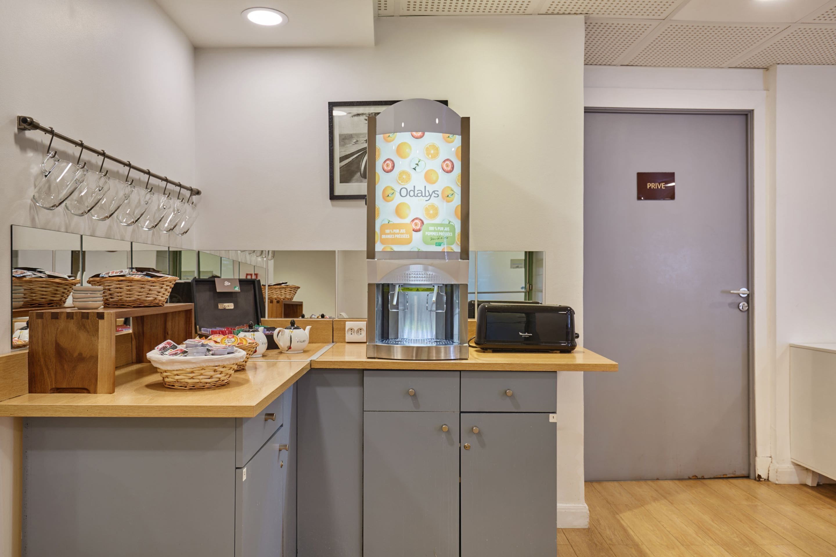 A kitchenette with a coffee machine, toaster, and baskets of bread.
