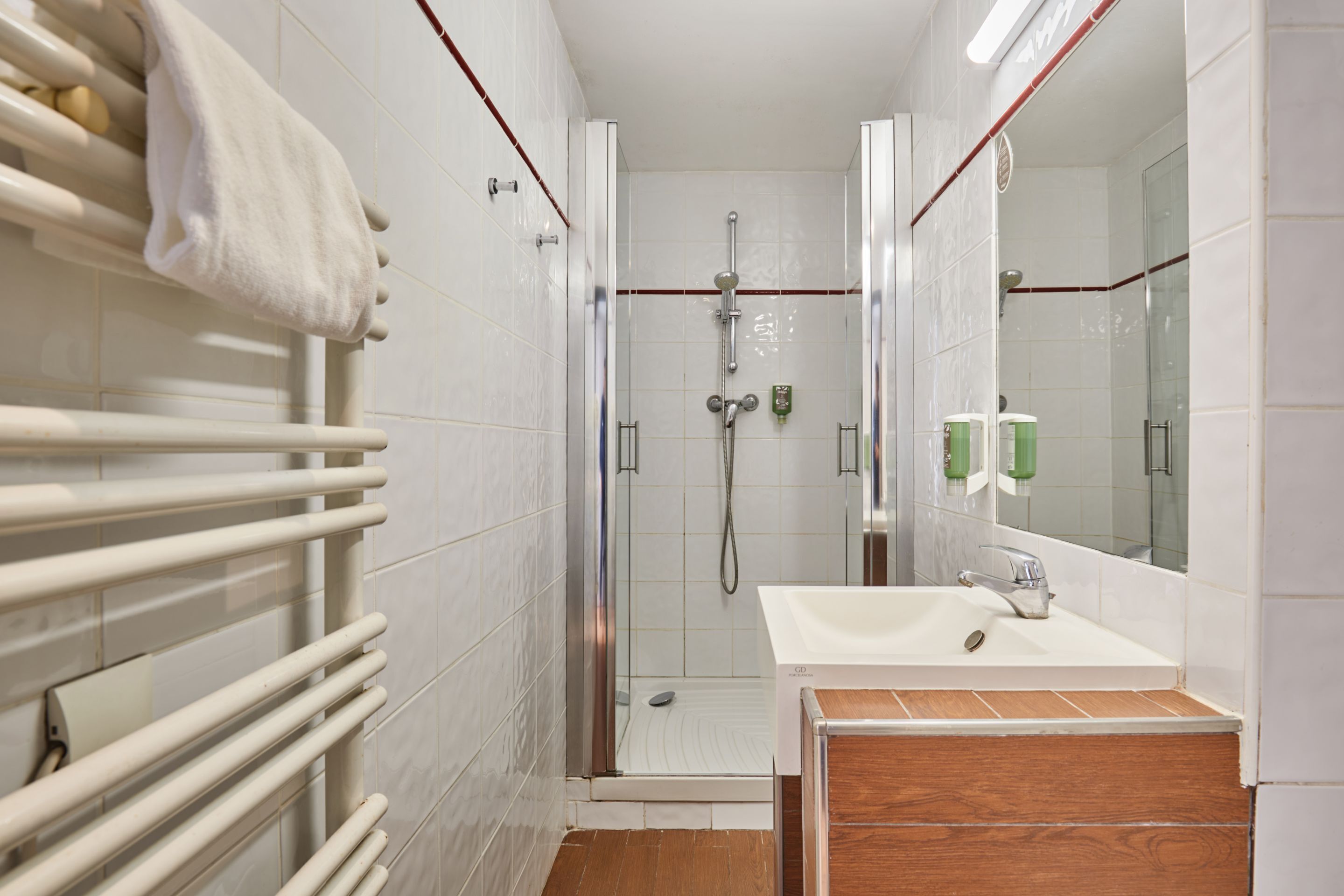 A modern bathroom with a glass-enclosed shower, a white sink, and a wooden vanity.