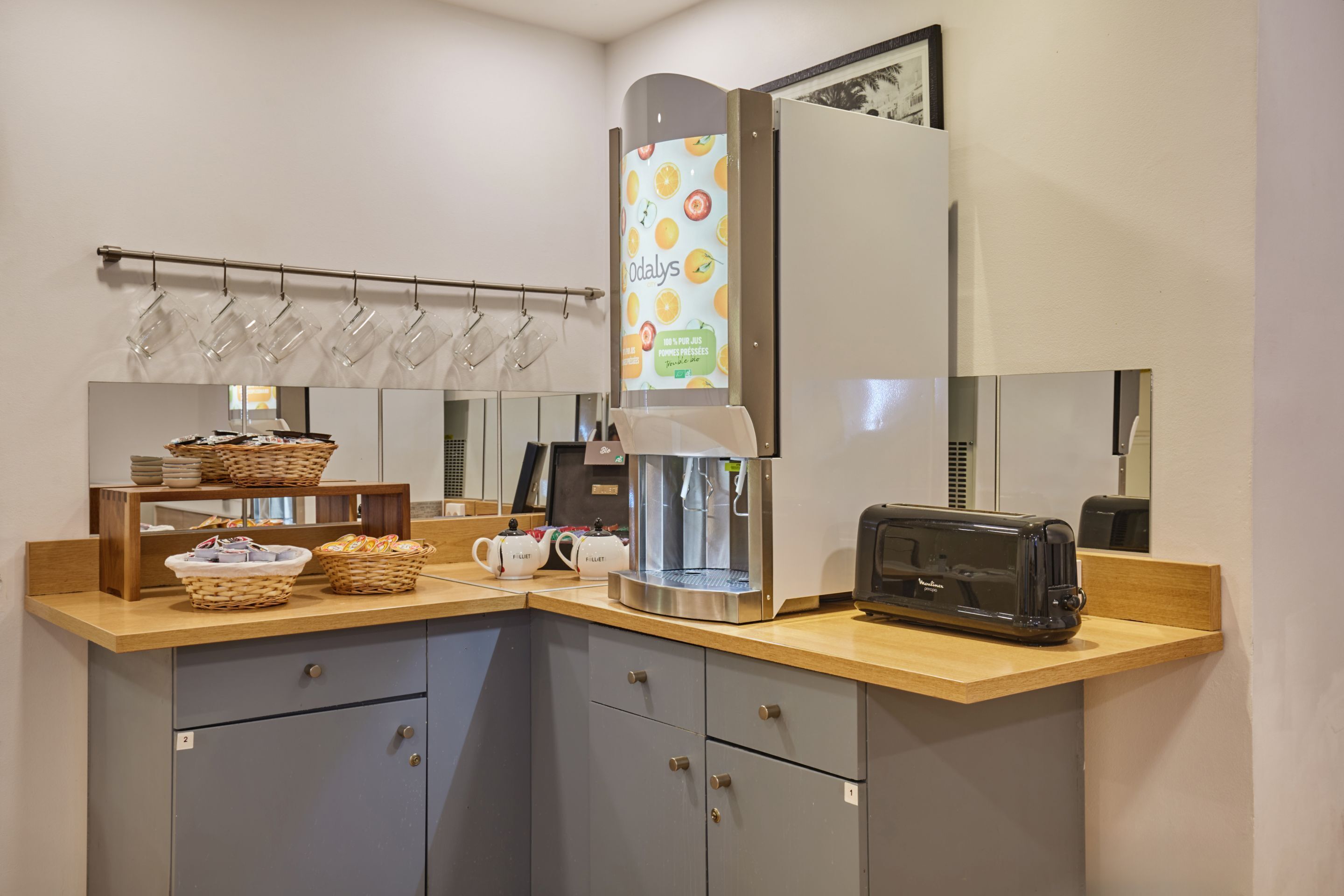 A kitchenette with a coffee maker, toaster, and hanging mugs.