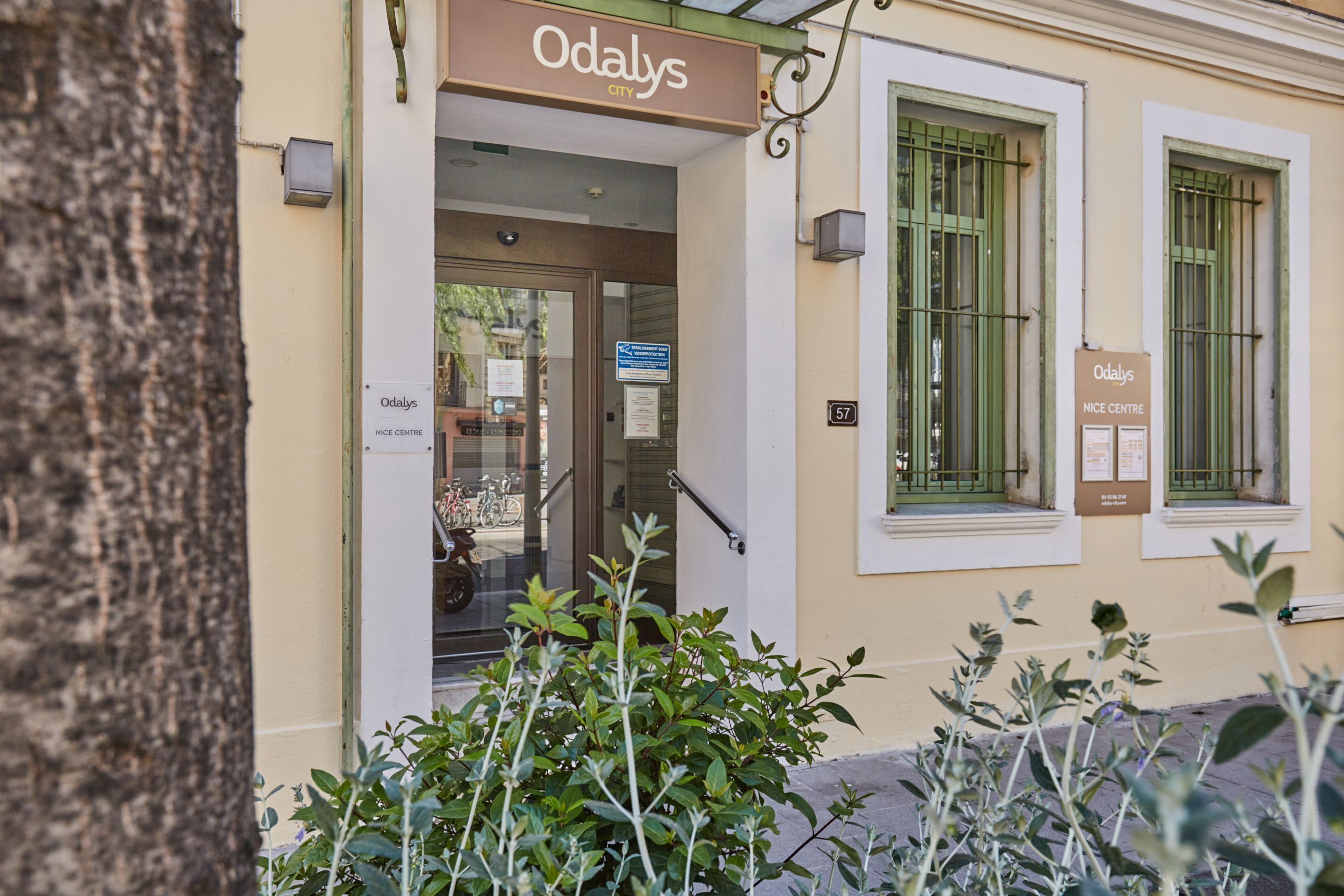 A building entrance with a sign reading 'Odaly's NICE CENTRE' and a number '57' on the wall.