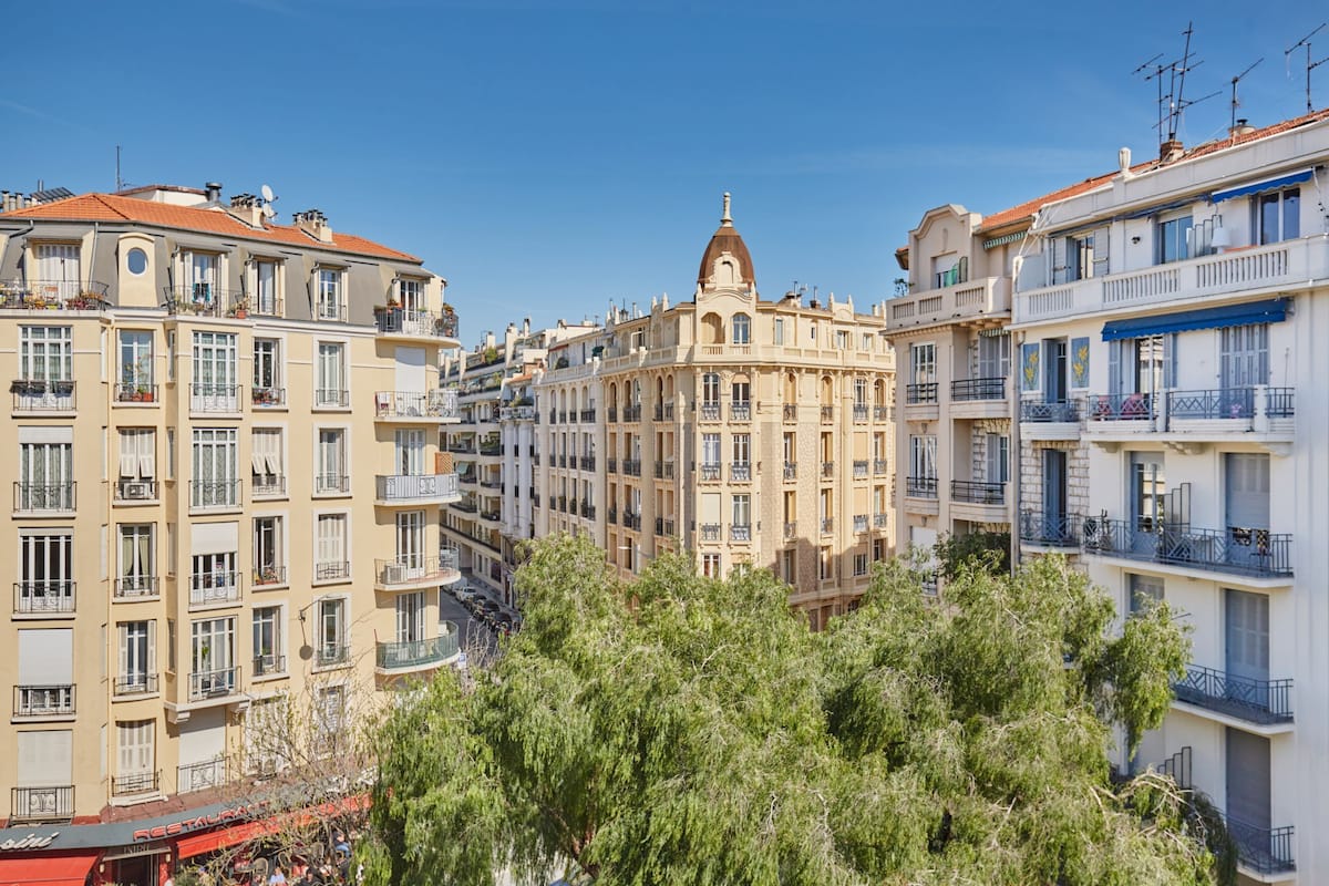 Un edificio de varios pisos con balcones, una cúpula central y árboles circundantes.