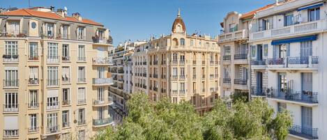 A multi-story building with balconies, a central dome, and surrounding trees.