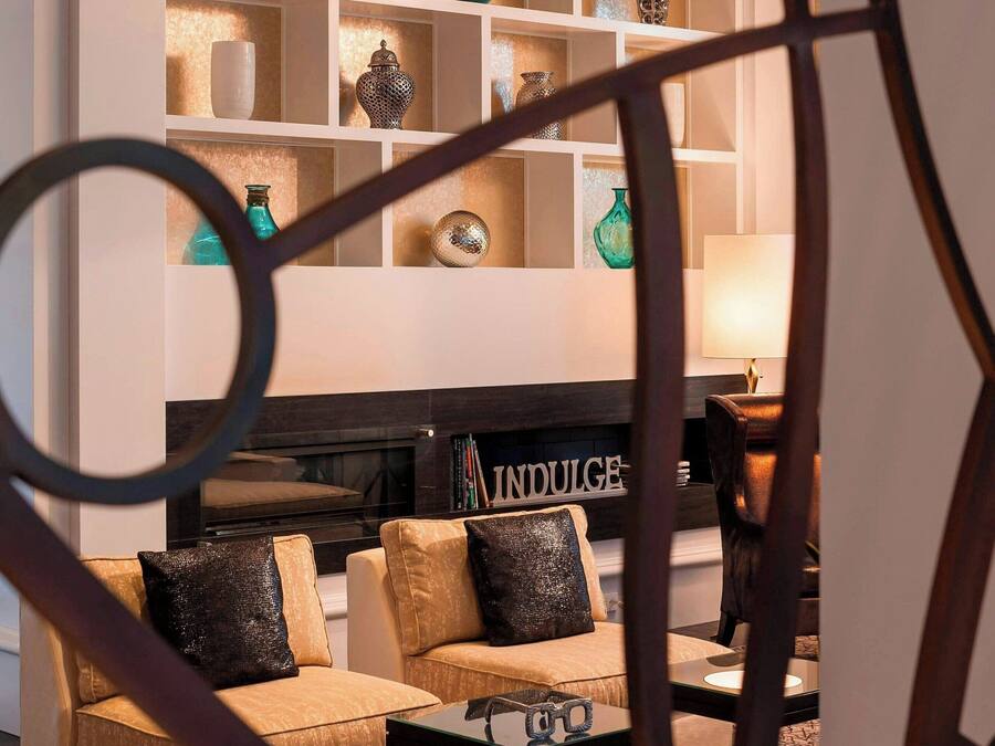 Una sala de estar moderna con chimenea, sofás y una mesa de centro. Se ven estanterías con objetos decorativos.