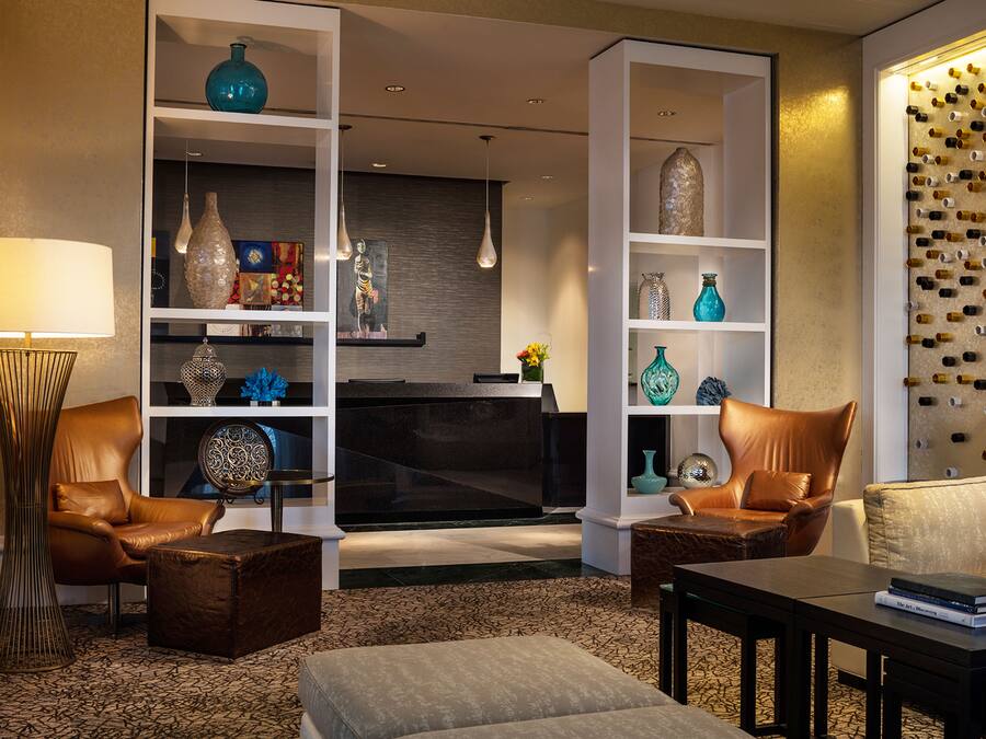 A modern living room with leather chairs, a coffee table, and a bookshelf with decorative items.