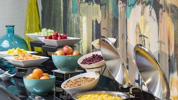 En buffet med forskellige retter og et farverigt abstrakt maleri i baggrunden.