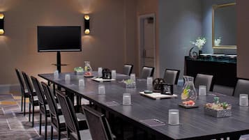 A conference room with a long table, chairs, a TV, and decorative items.