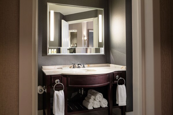 A bathroom with a large mirror, a sink, and a towel rack.