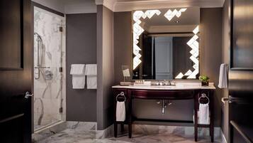Een moderne badkamer met een douche in marmer, een wastafel met spiegel en een handdoekrek.