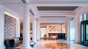 Um hall espaçoso com design moderno, apresentando uma área de estar central, uma parede decorativa e uma recepção bem iluminada.