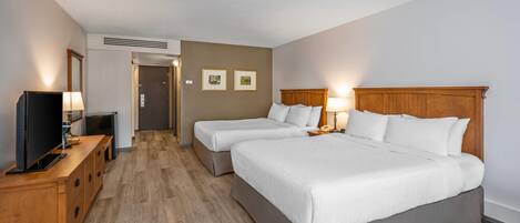Ett hotellrum med två sängar, en TV, ett skrivbord och en spegel.