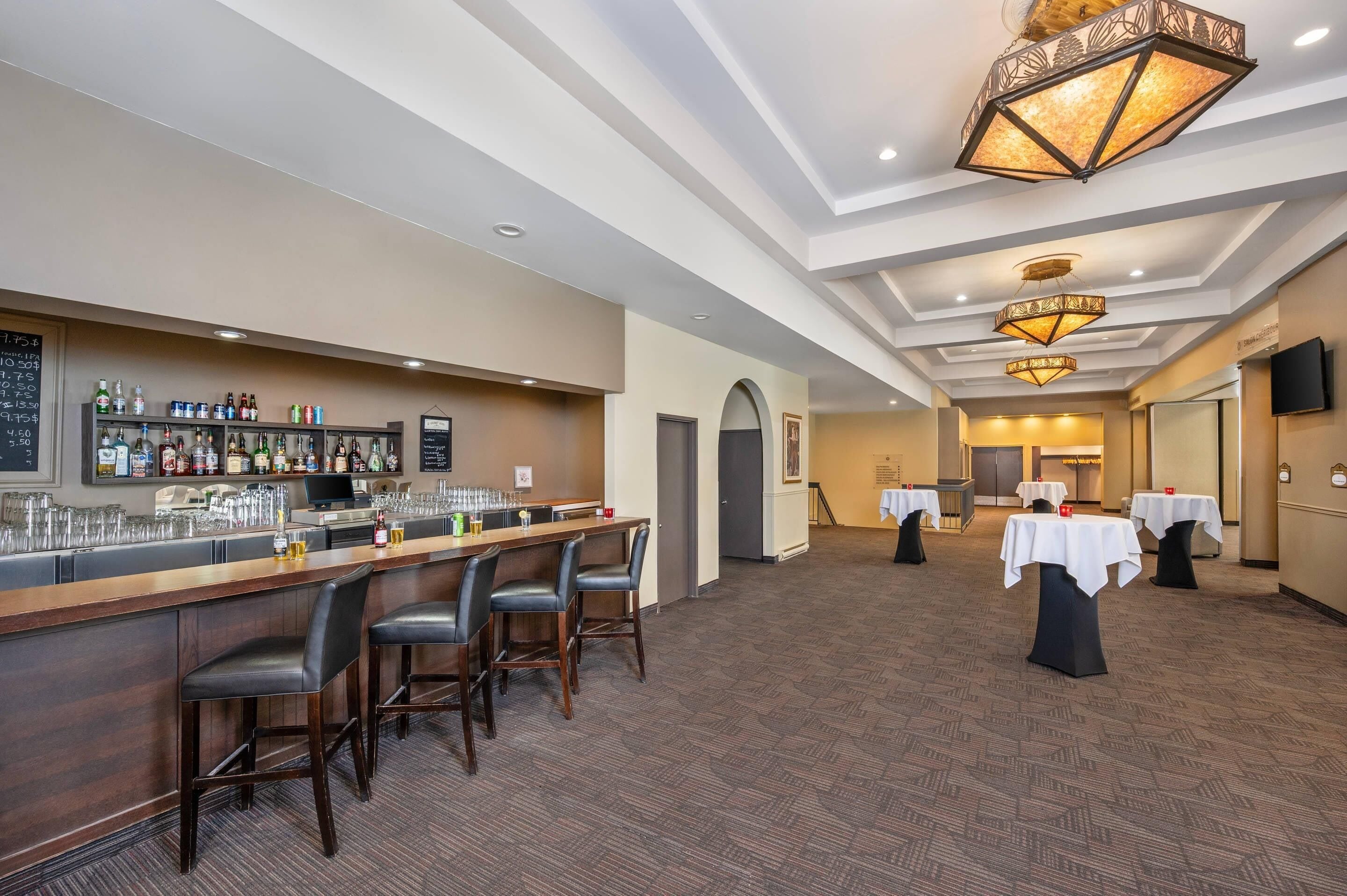 A bar area with a long counter, multiple stools, and a variety of bottles and glasses.