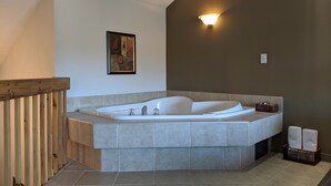 Un baño moderno con una bañera independiente, baranda de madera y una obra de arte enmarcada en la pared.