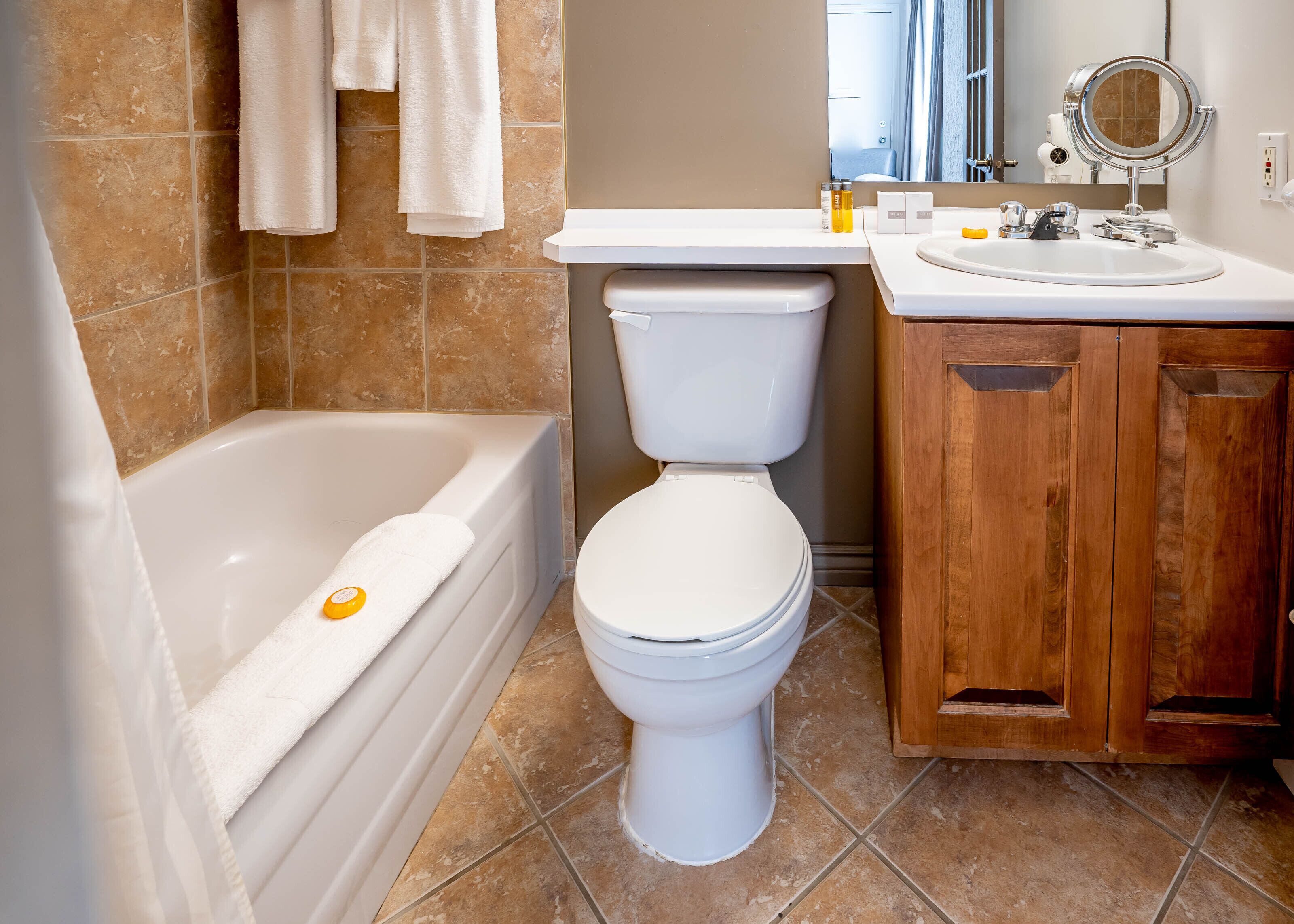 Un baño con bañera, inodoro y armario de madera.