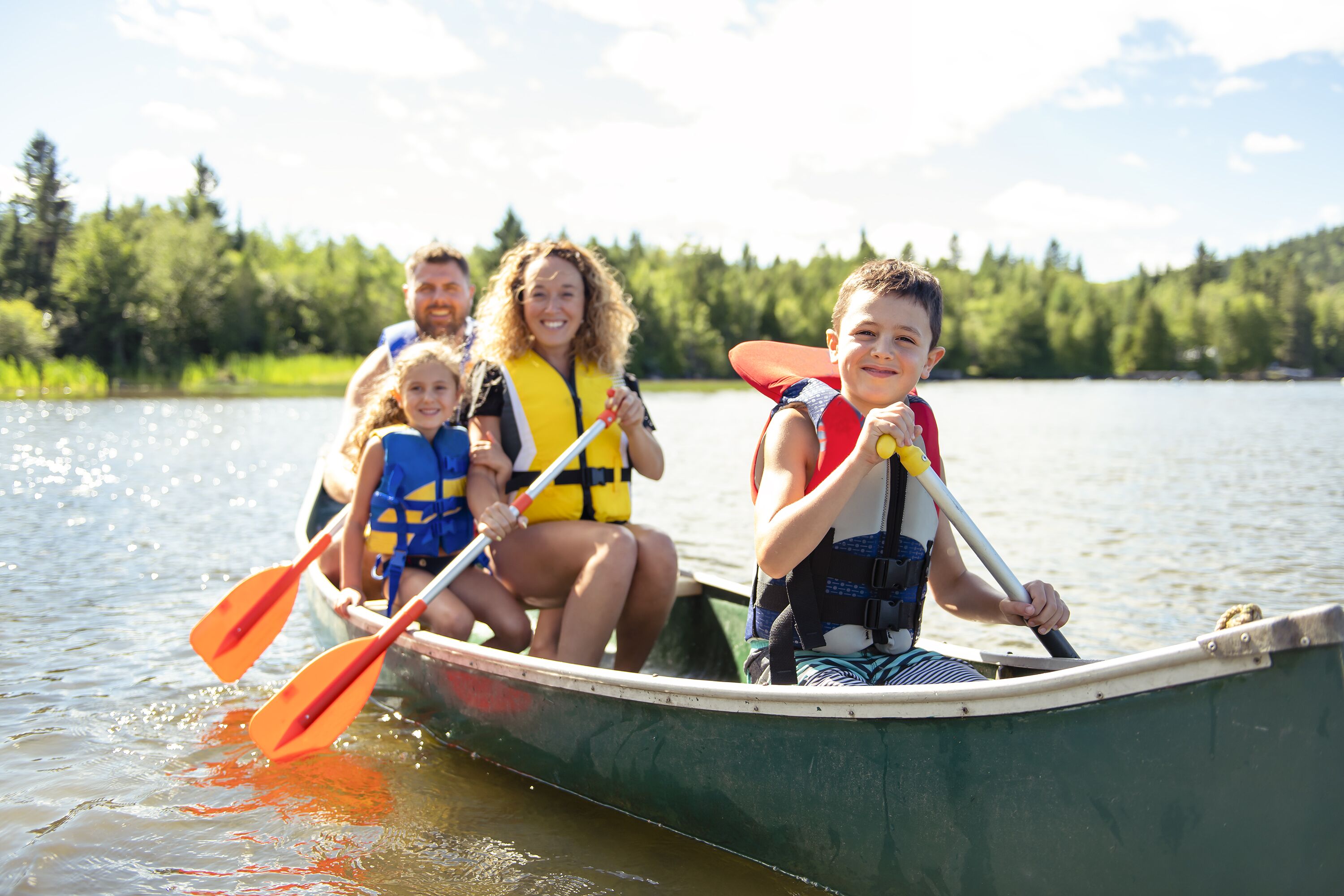 A family in a canoe on a lake surrounded by trees.