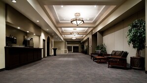 Un hall de hotel con mostrador de recepción, zona de estar y una gran lámpara de araña.