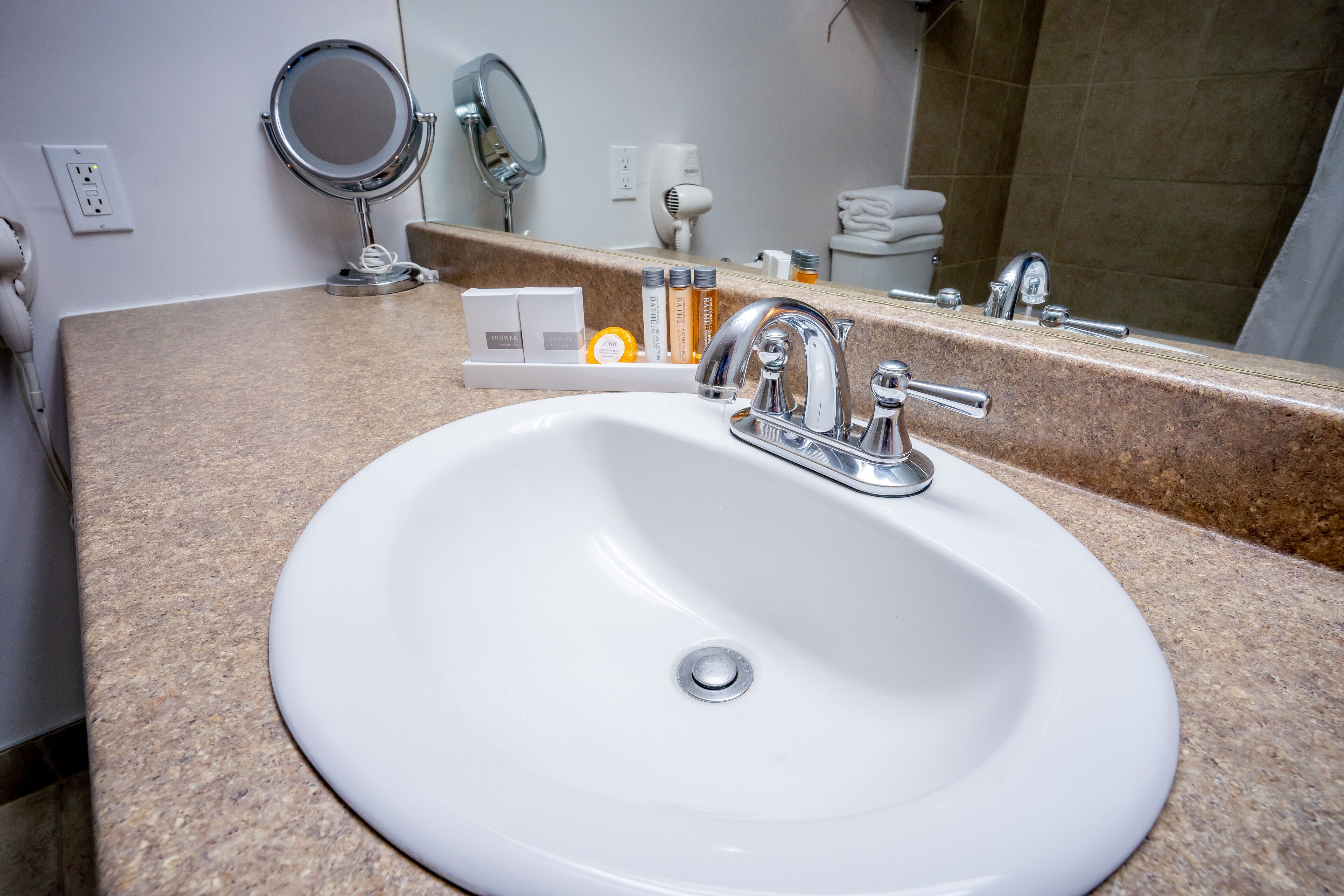 Une salle de bain avec un lavabo blanc, un miroir et des articles de toilette posés sur le comptoir.