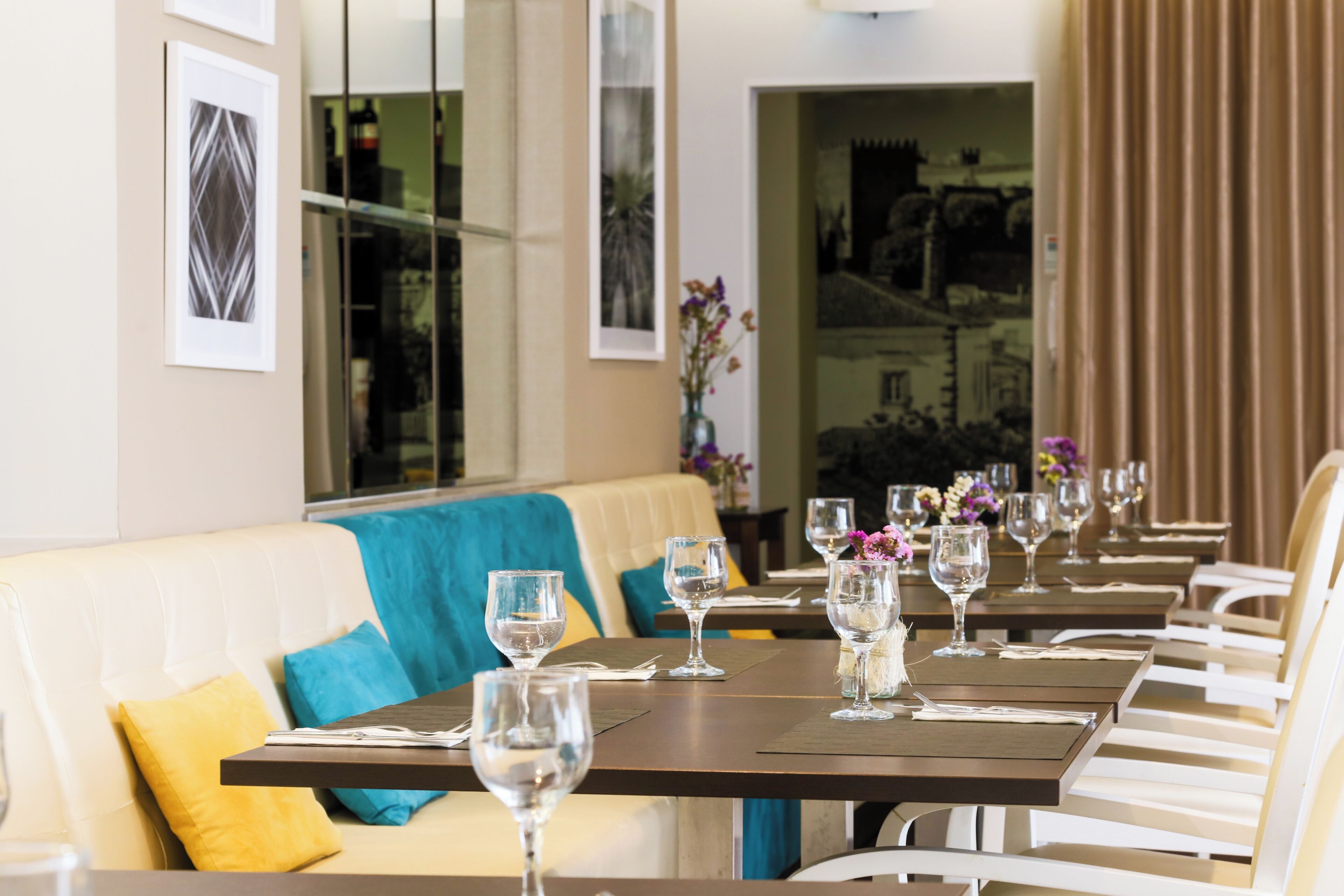 A restaurant with tables set for dining, a sofa with cushions, and framed artwork on the walls.