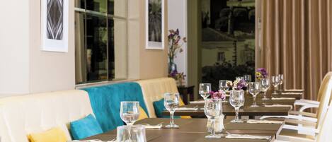 Un restaurant avec des tables dressées pour le service, un canapé agrémenté de coussins et des œuvres d’art encadrées accrochées aux murs.
