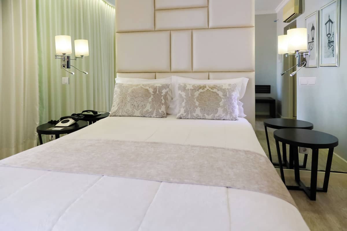 Ett hotellrum med en stor säng, två sängbord, en telefon och väggmonterade lampor.