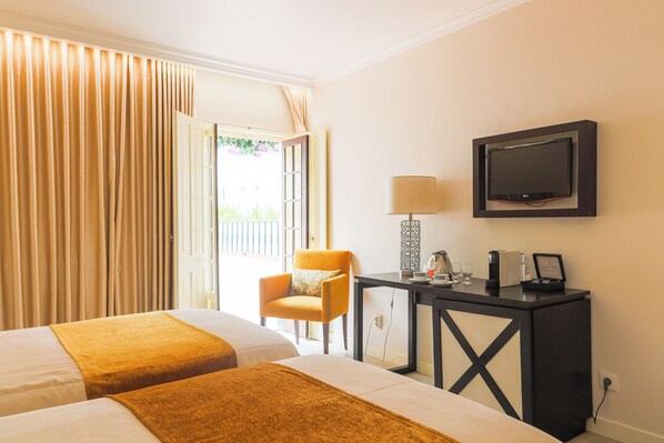 Une chambre d’hôtel avec deux lits, un bureau avec une lampe, une télévision et une chaise.