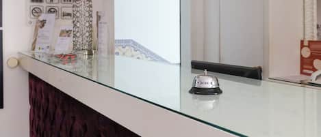 A reception desk with a glass top, a red lamp, and a bell.
