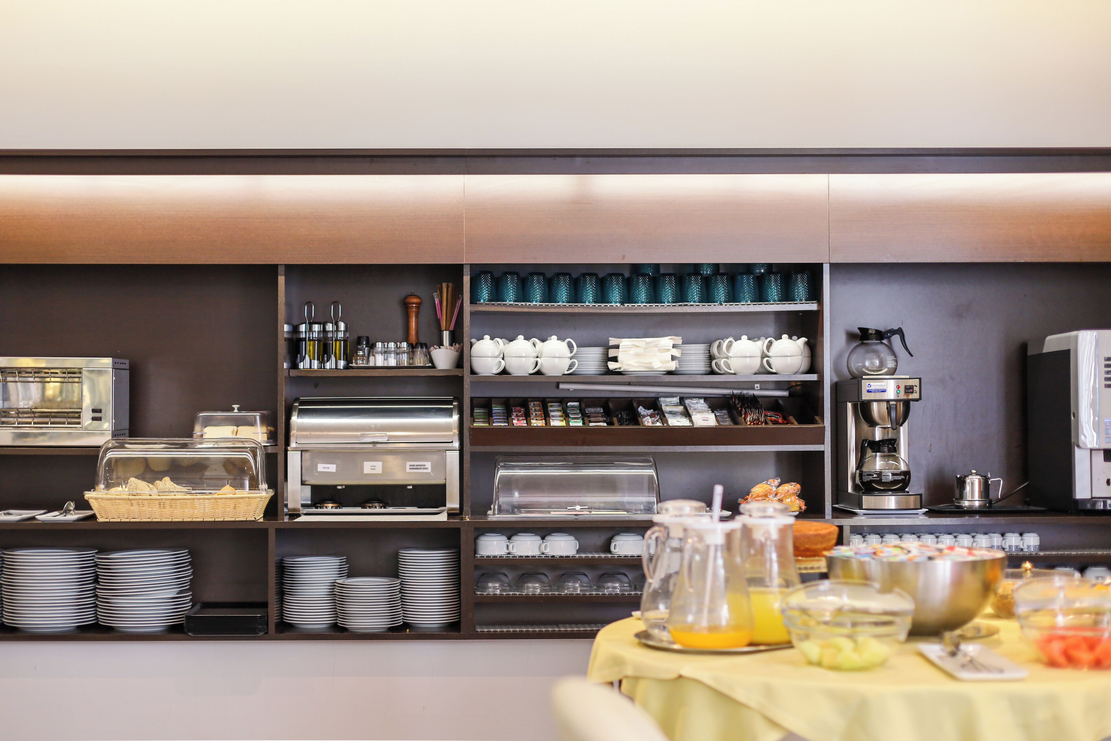 A breakfast buffet with various food items and beverages, including a coffee machine and tea pots.