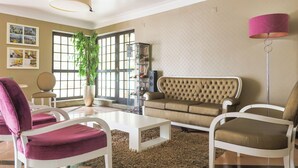A living room with a beige sofa, white armchairs, a white coffee table, and a large window with a view of the outside. - Josefa D'Óbidos (Obidos)