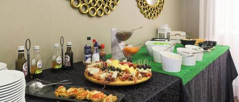A buffet table with various food items and condiments, surrounded by decorative wall mirrors and a green tablecloth.
