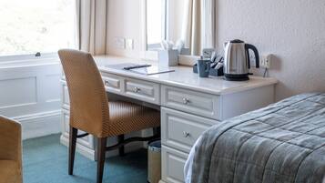 A hotel room with a desk, chair, bed, and a window with curtains.