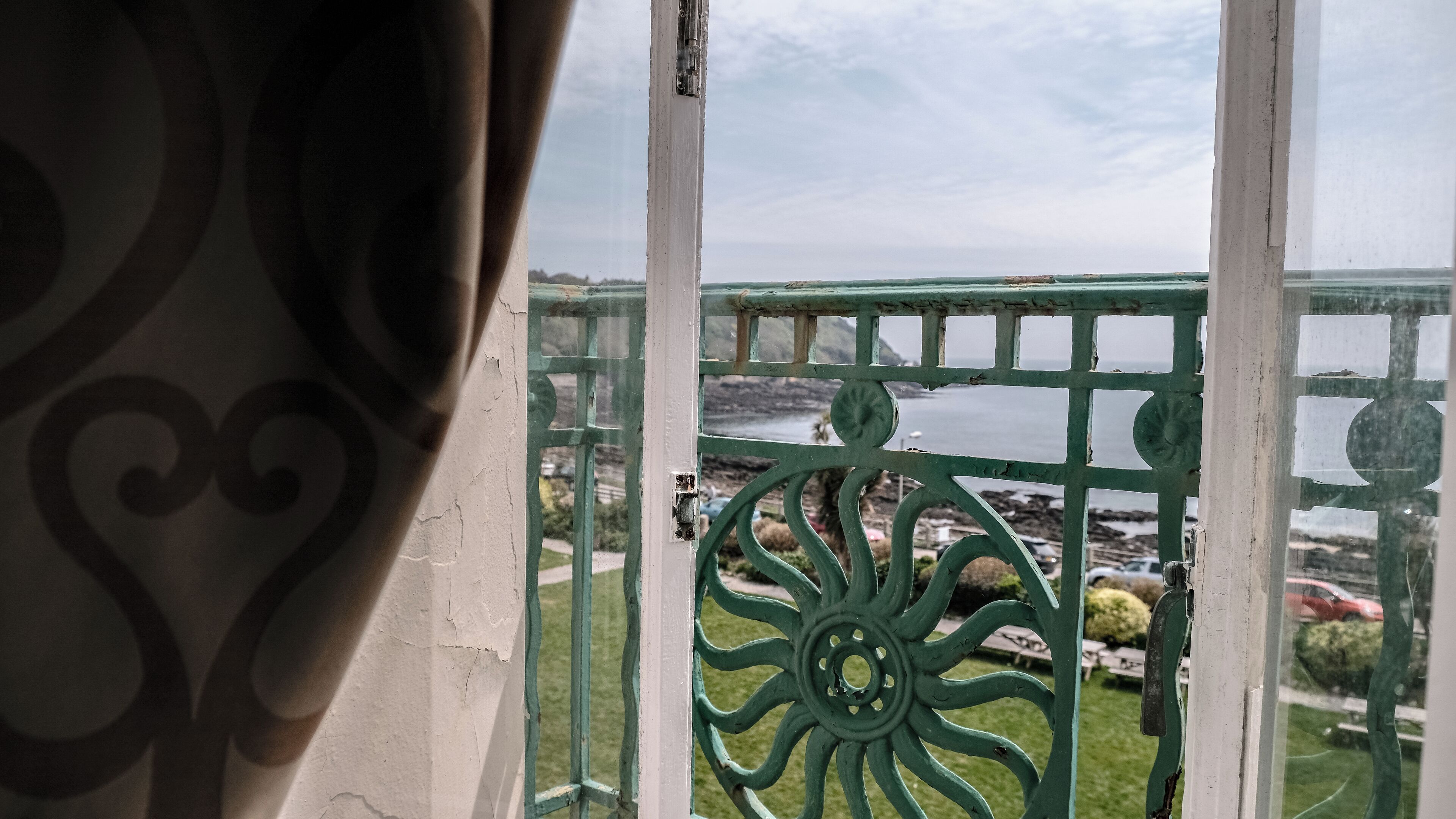 A balcony with a view of a body of water and rocky shoreline.