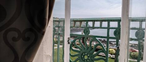 A balcony with a view of a body of water and rocky shoreline.