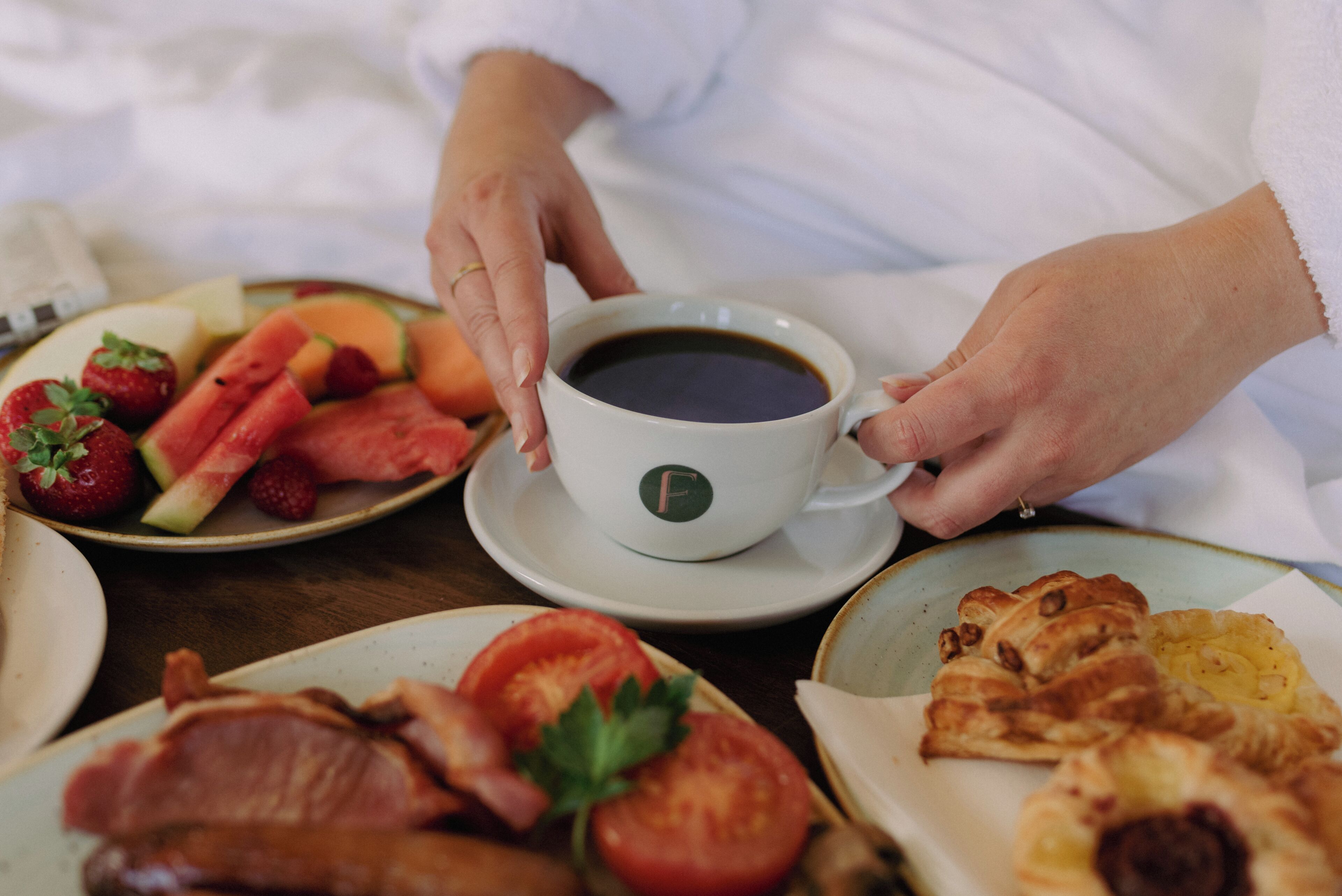 Desayuno con una taza de café, fruta y pasteles.