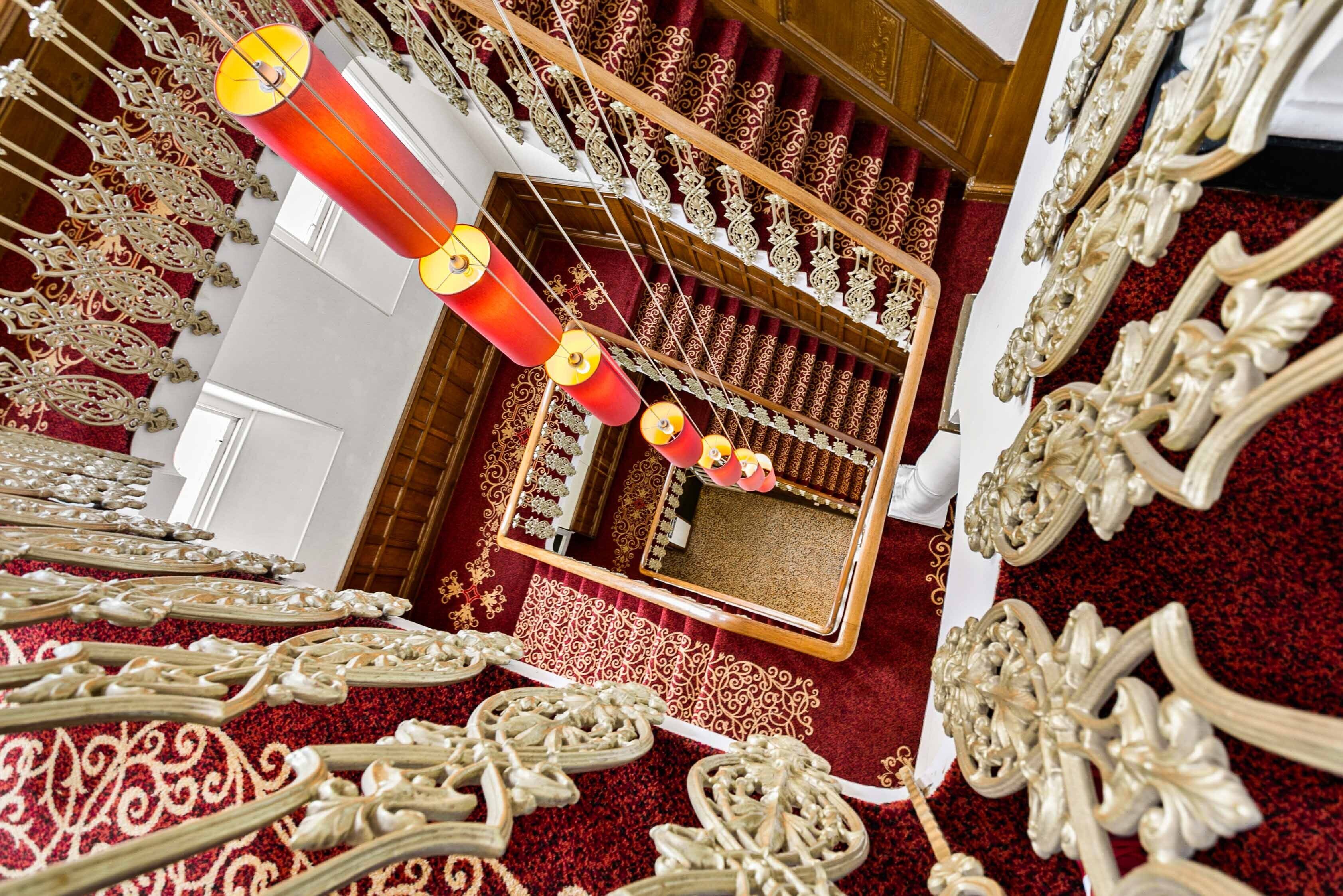 Un vaste hall agrémenté de lustres somptueux, d’un sol recouvert d’un tapis rouge et de décorations murales élaborées.