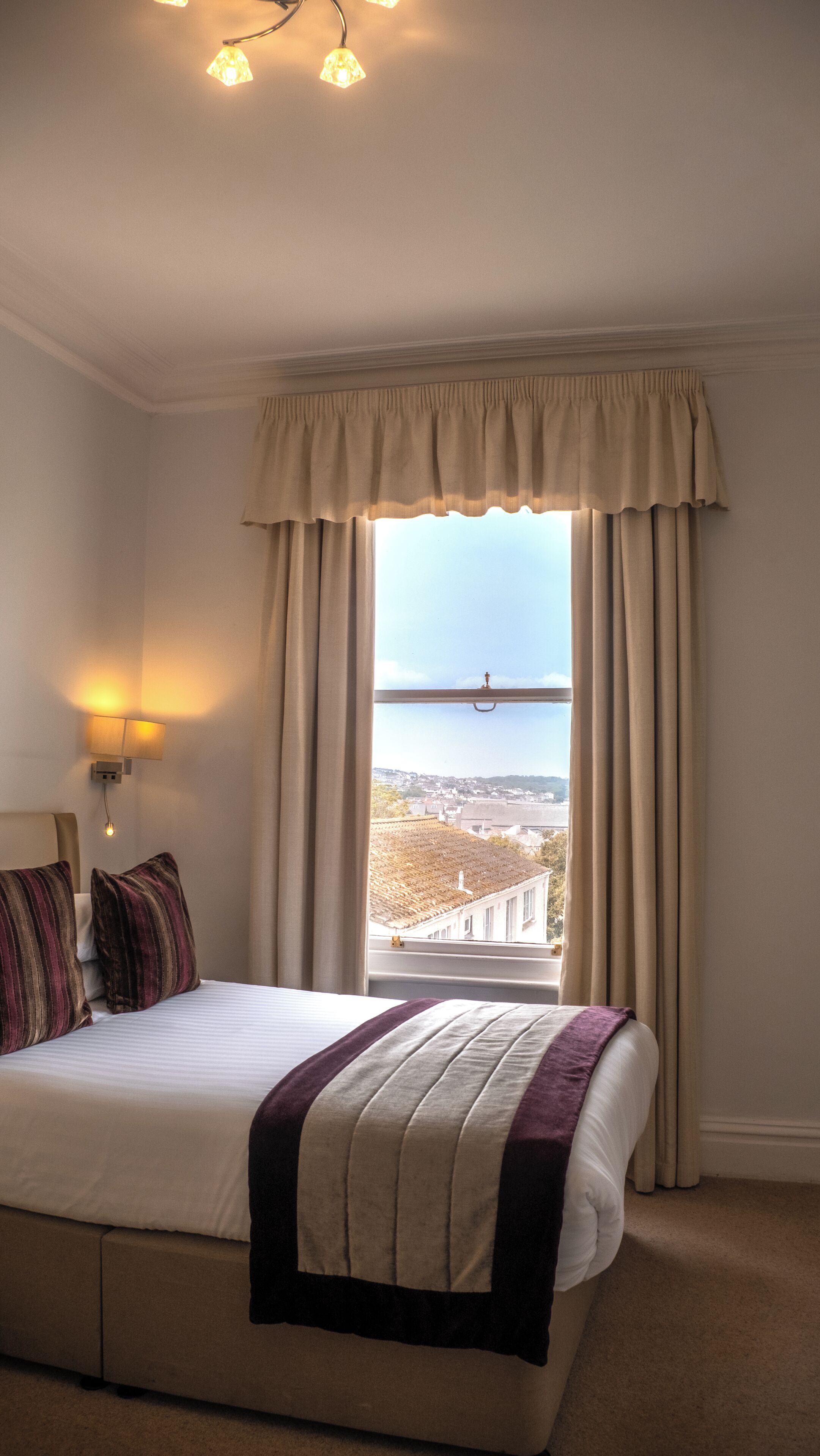 Ein Hotelzimmer mit einem großen Bett, Blick auf die Stadt und einem Vorhangfenster.