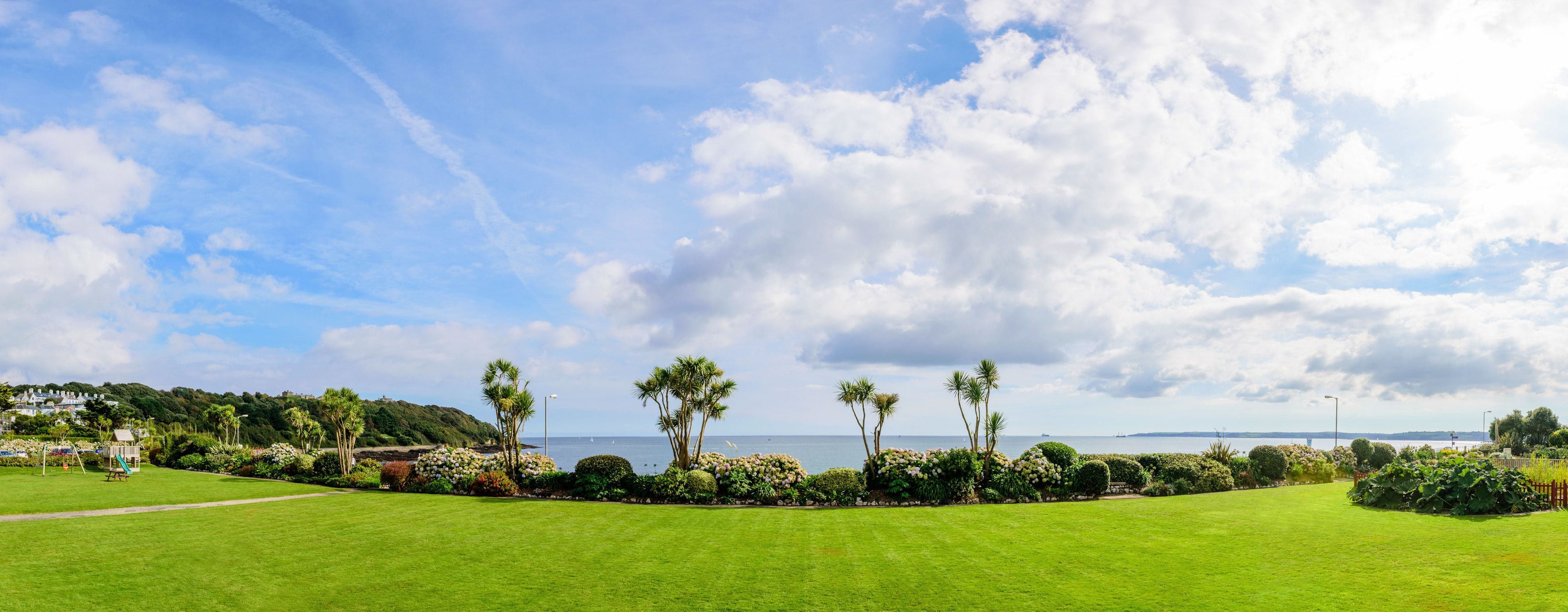 A well-maintained grassy area with a clear view of the ocean and a distant shoreline.