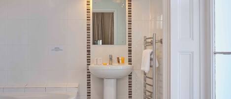 A modern bathroom with a white sink, mirror, and bathtub.