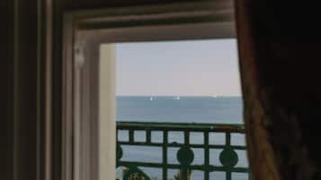 A view through a window with a metal railing, overlooking a body of water with sailboats.