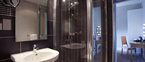 A modern bathroom with a white sink, a mirror, and a shower area.