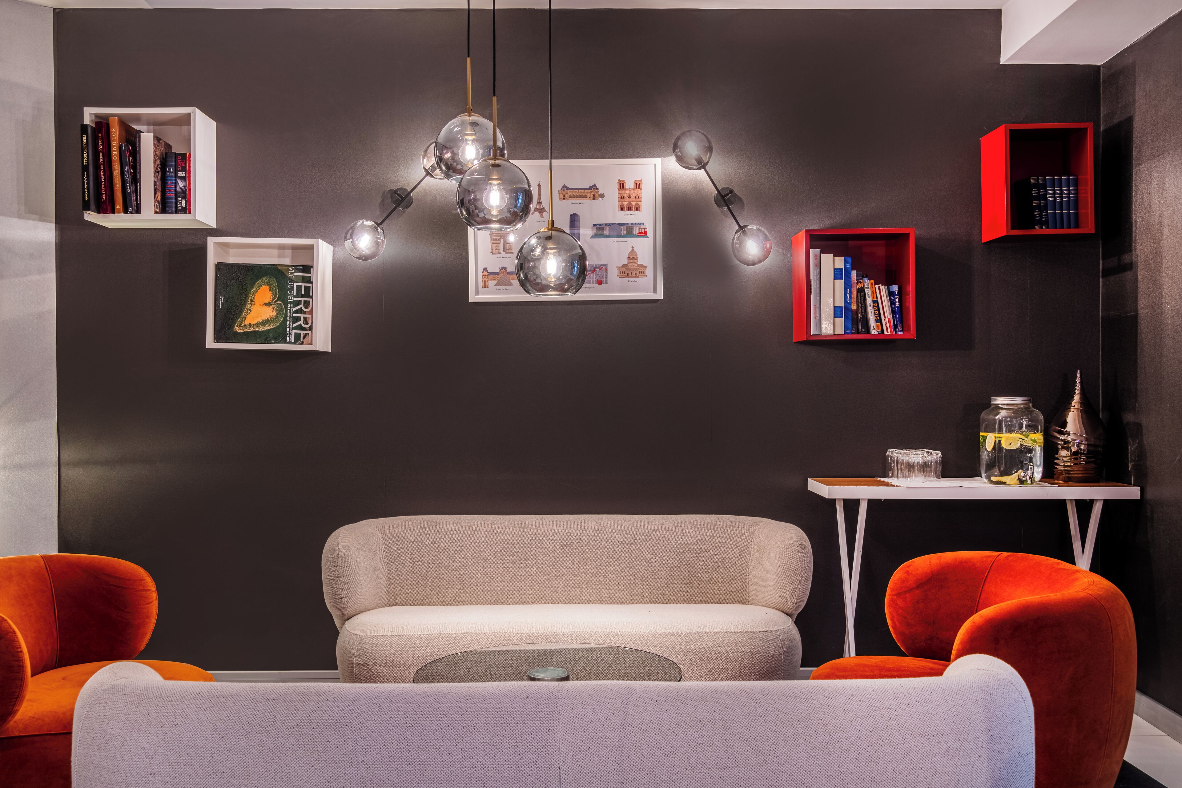 A modern living room with a sofa, two armchairs, a coffee table, and a small side table with books and decorative items.