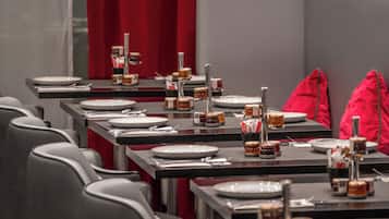 Um restaurante com mesas preparadas para refeições, cada uma com pratos, talheres e acompanhamentos.