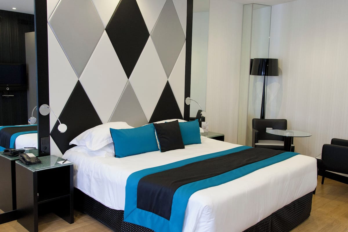 Une chambre d’hôtel moderne avec un grand lit, une table de chevet, un bureau, une chaise et une lampe.