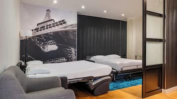 A hotel room with two beds, a sofa, a large mural of the Eiffel Tower, and a blue carpet.