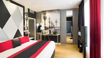 A modern hotel room with a large bed, a desk, and a television.