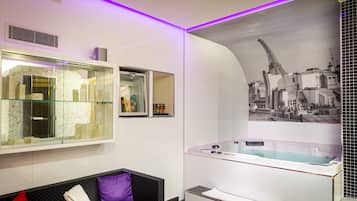 A modern bathroom with a glass-enclosed shower, a large bathtub, and a cityscape mural on the wall.